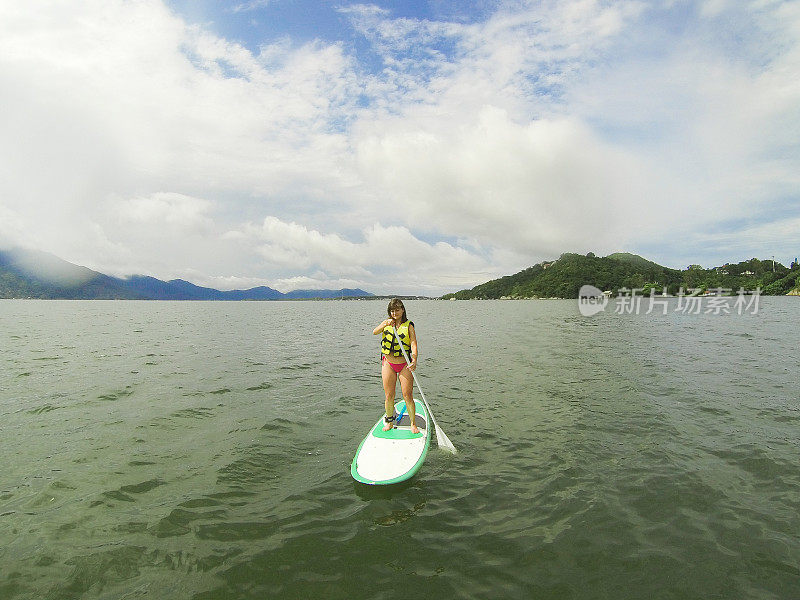 年轻女子站着划桨