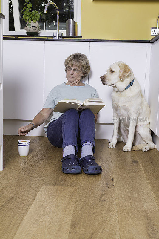 老夫人和她的狗坐在厨房地板上