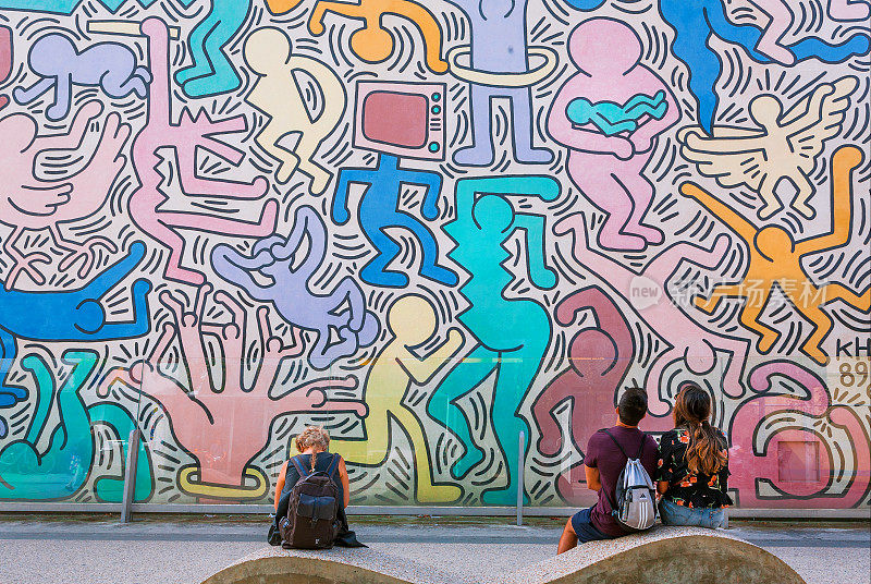 人们在墙上观看现代艺术家基思·哈林的艺术作品，他以流行艺术风格闻名