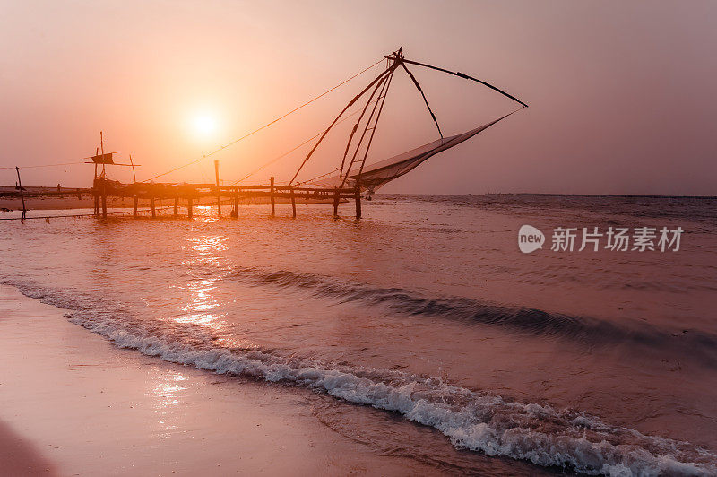 热带海滩上的日落。中国渔网在科钦的海洋海岸景观剪影。南印度，喀拉拉邦，科钦
