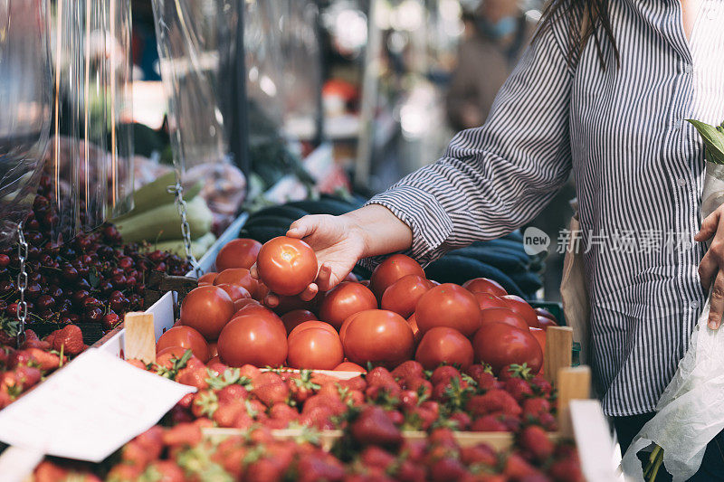 健康饮食理念:农贸市场上，一个大号女人手拿新鲜番茄