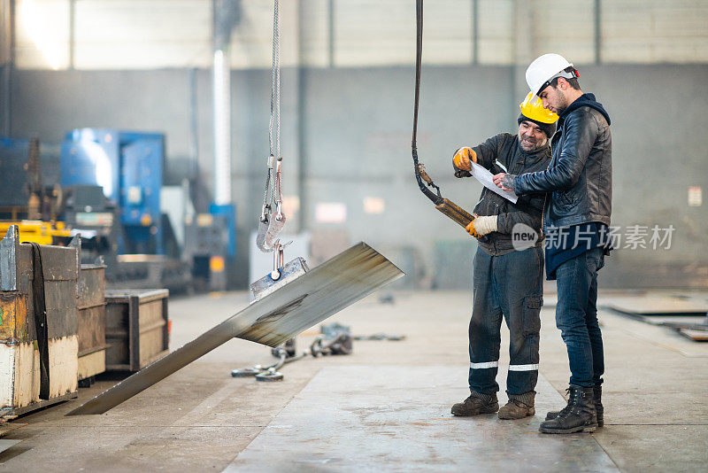 年轻工程师根据检查表检查使用缆索绞车的工厂工人的工作