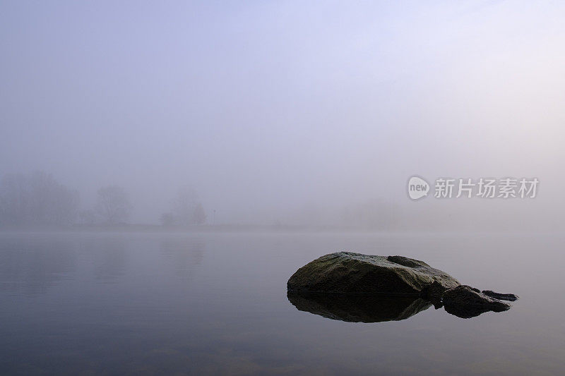 岩石在河在一个雾蒙蒙的风景在河的三角洲IJssel在冬天