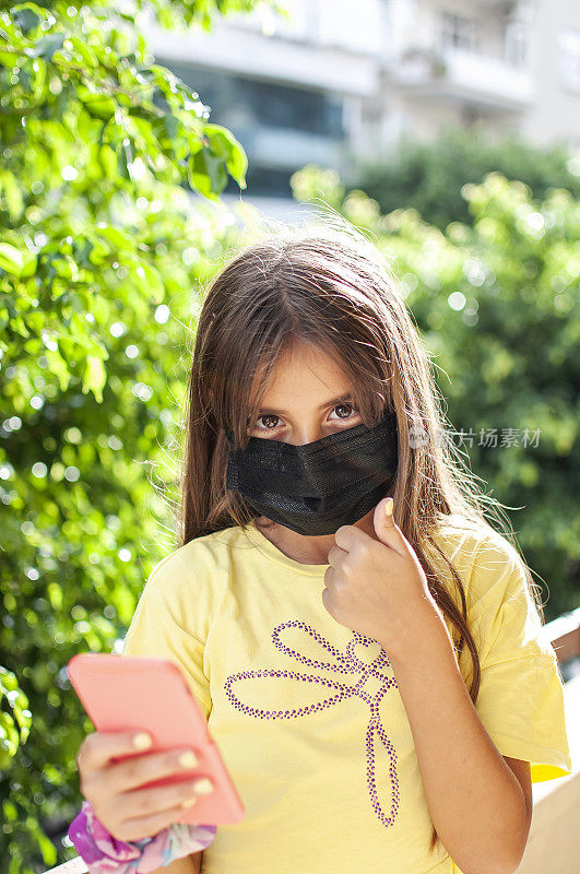 一个女孩的肖像戴着防护面具和手机
