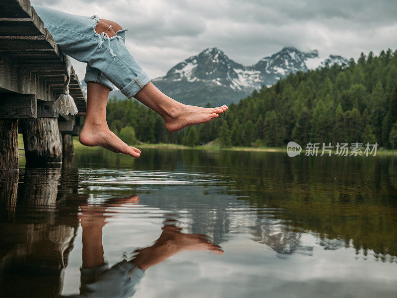 双脚悬在湖边码头上