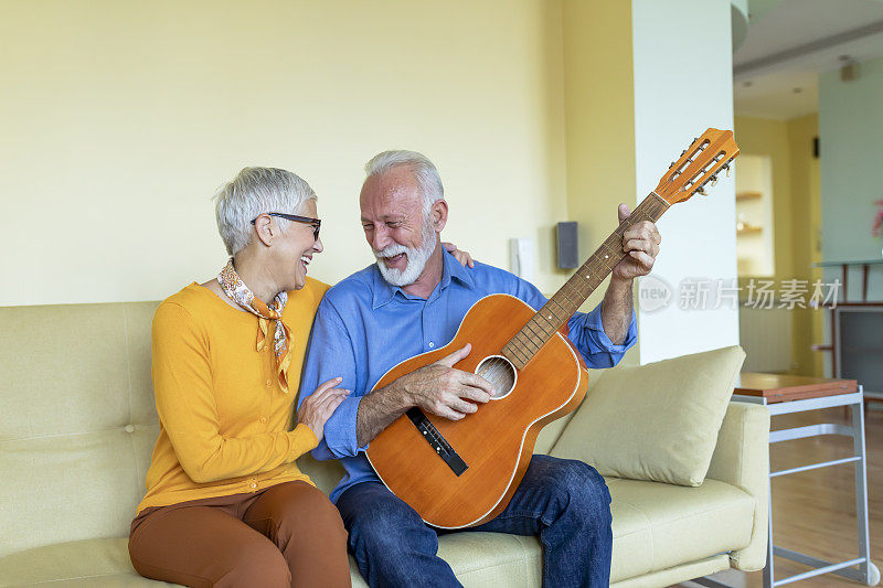 一位快乐的退休老人正在为他美丽的妻子弹吉他，他的妻子喜欢轻松的音乐。