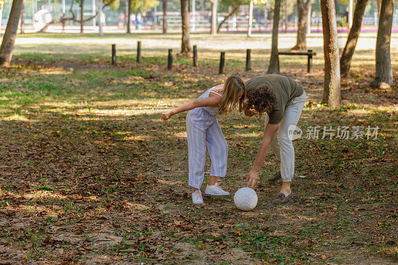 快乐的爸爸和女儿在享受大自然，踢足球。