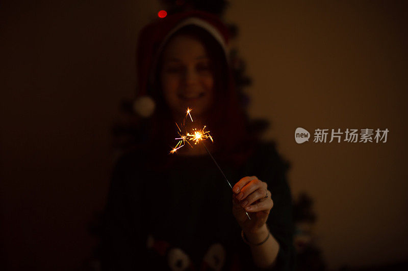 幸福微笑的白种女人拿着烟花。圣诞节和新年时间在家。