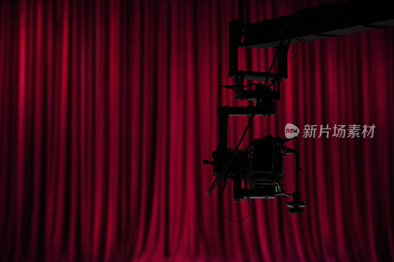 红丝绒窗帘前的起重机上的摄像机