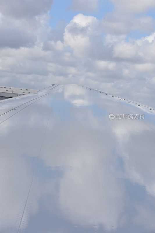 飞机机翼上云朵的倒影