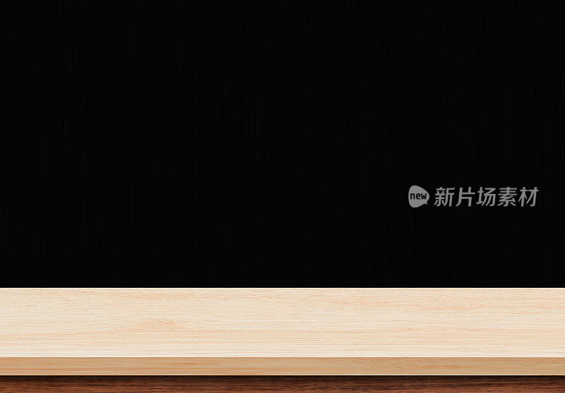 黑色墙壁上的空木桌，用于展示或蒙太奇您的产品。