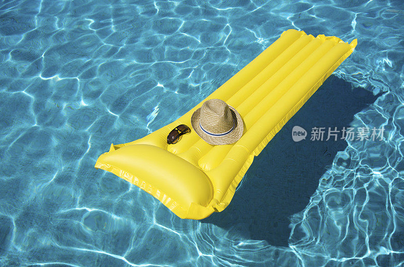 黄色的池筏浮着帽子和太阳镜