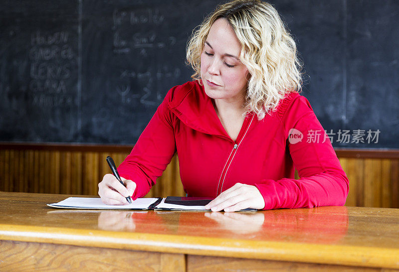 一个金发女人在教室里的课桌上写作