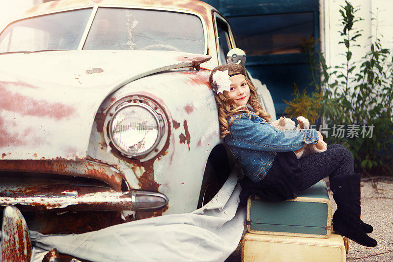 玩具熊和古董车旁的小女孩