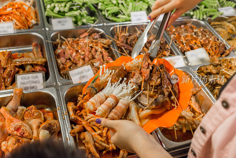 妈妈和儿子在烧烤自助餐上挑选食物