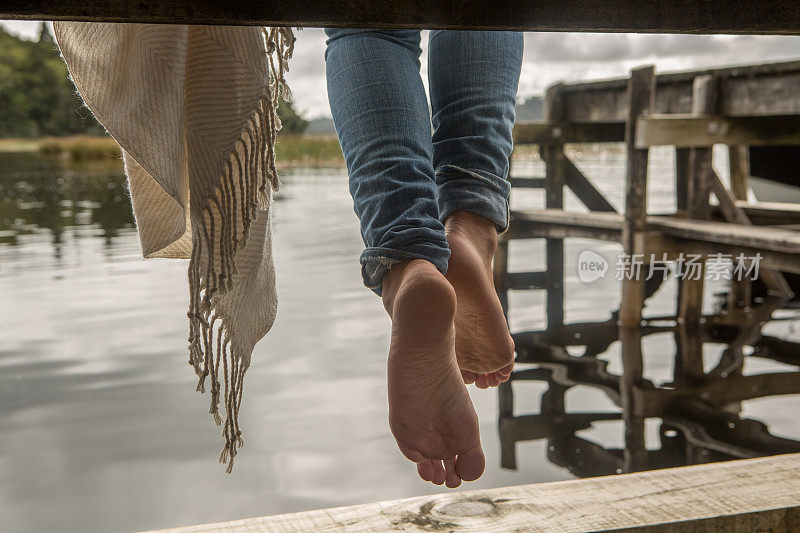 新西兰，一个女人的脚悬在湖边码头上