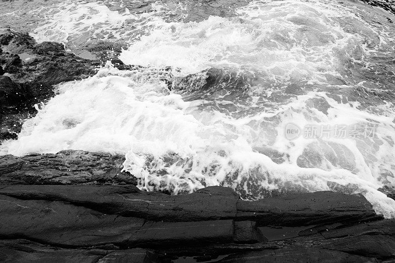 黑色和白色的海浪拍打着岩石海岸
