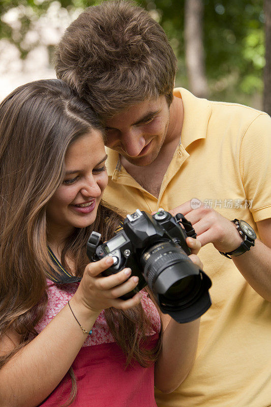 一对快乐的年轻夫妇看着他们的相机