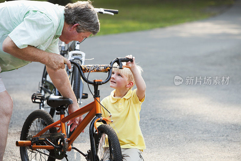 爷爷帮小男孩骑自行车