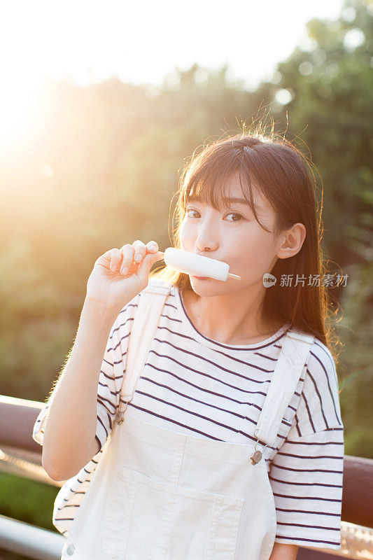 年轻美丽的女人在大自然中吃着美味的冰淇淋