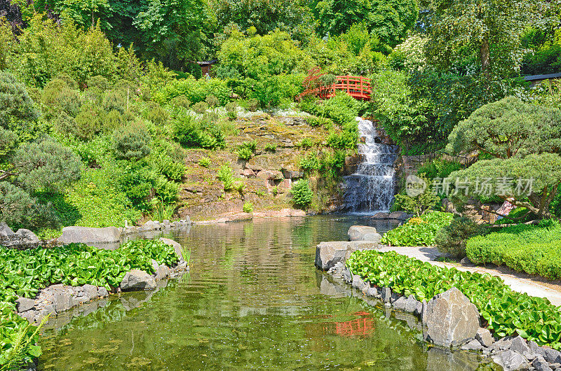 红色人行桥与瀑布和湖在日本花园