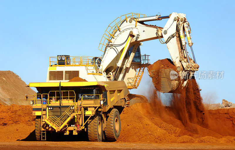 挖掘机将矿石装载到运货卡车上。