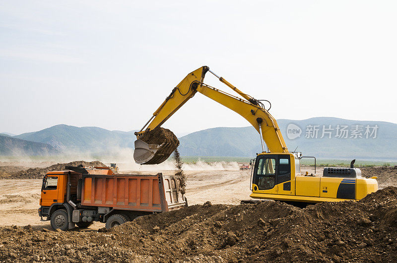 在挖掘机的帮助下，用自卸卡车处理地面