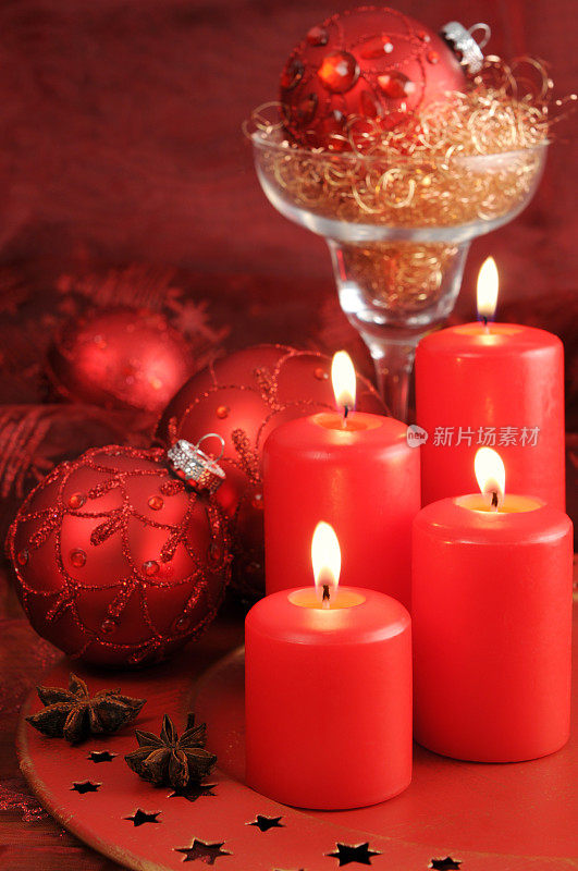 四支燃烧的降临节蜡烛，上面有圣诞节的红色装饰