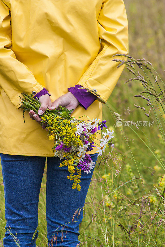 穿着黄色雨衣的女人拿着野花