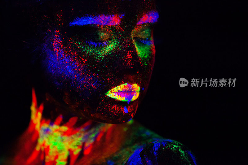 霓虹灯下美丽的外星模特。这是美丽的模特用荧光化妆的肖像，女性在UV中摆姿势的艺术设计，彩色的化妆。孤立在黑色背景上