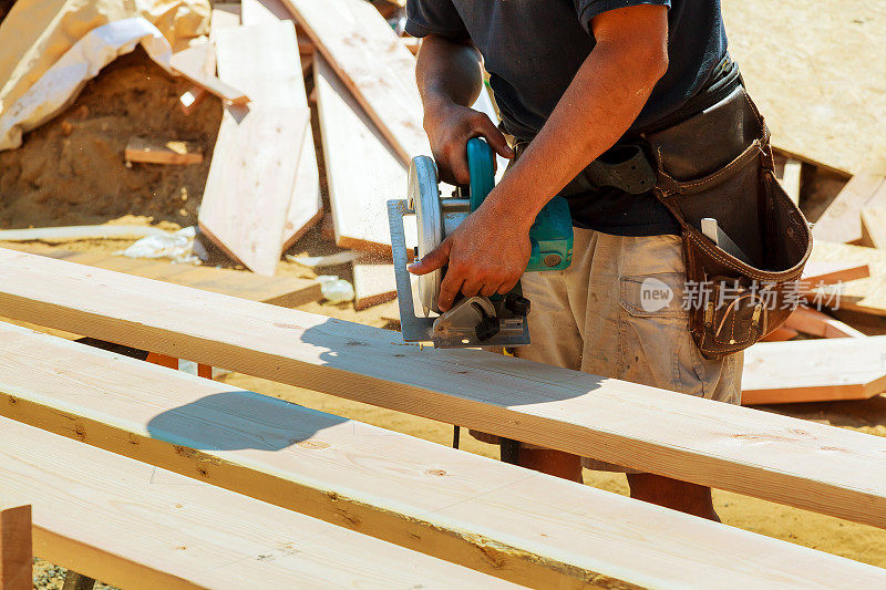 用圆锯切割木板的木匠。男工人或勤杂工的施工细节