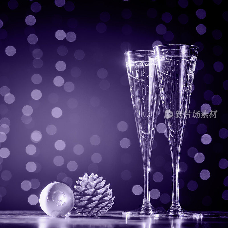 两杯香槟和圣诞玩具。节日灯光散景背景。紫外光色调，2018年度流行色