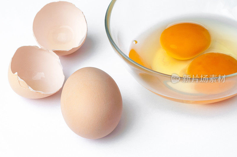鸡蛋，蛋壳和生蛋黄在玻璃上的特写孤立在白色的背景