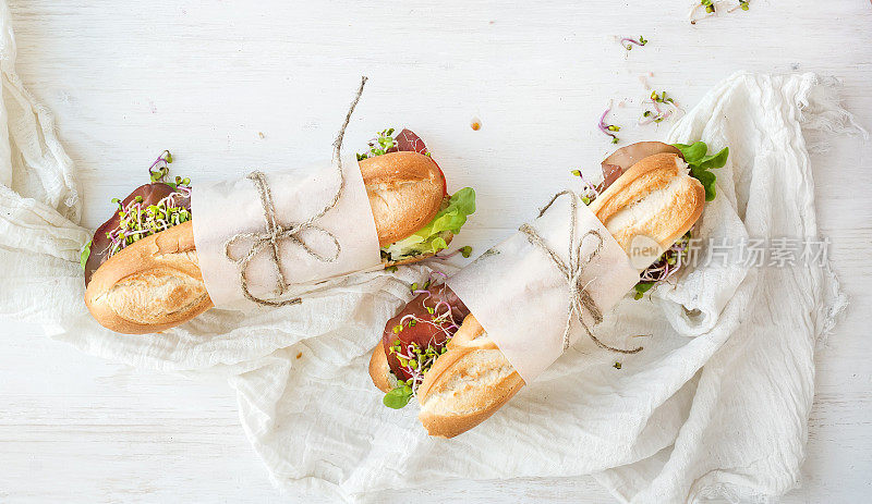三明治与牛肉，新鲜蔬菜和香草在白色的木材背景
