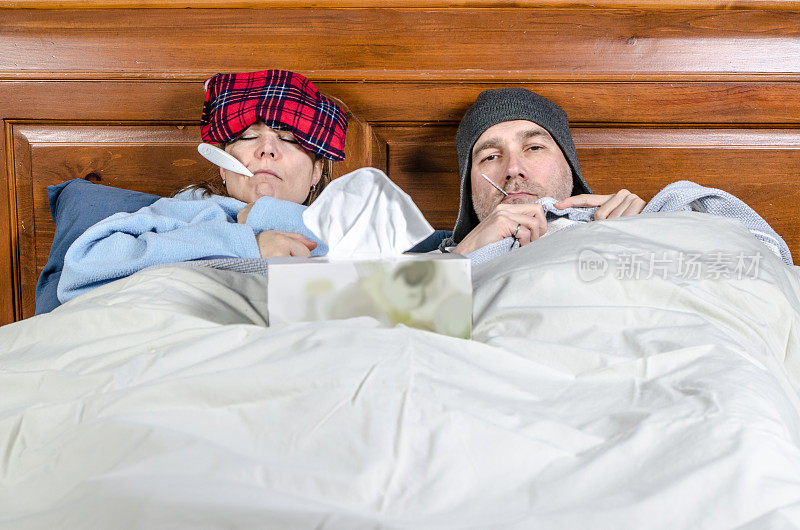 女人和男人躺在床上，嘴里含着温度计，还有一盒纸巾