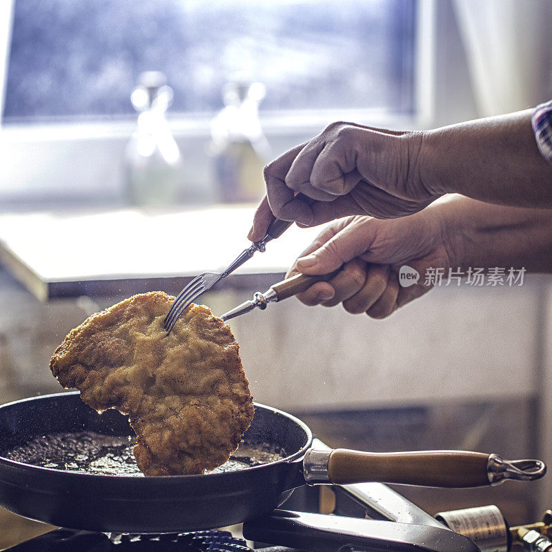 用平底锅在深油中煎炸维也纳炸肉排