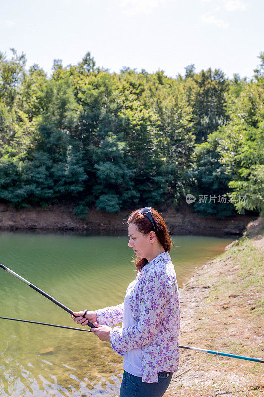 一个年轻女子在一个夏日阳光灿烂的晚上钓鱼。