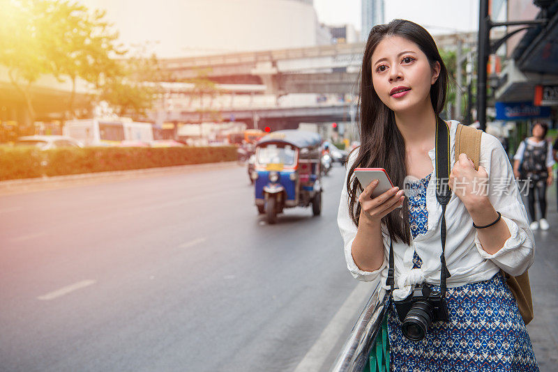 一名女子用手机应用程序在曼谷行走
