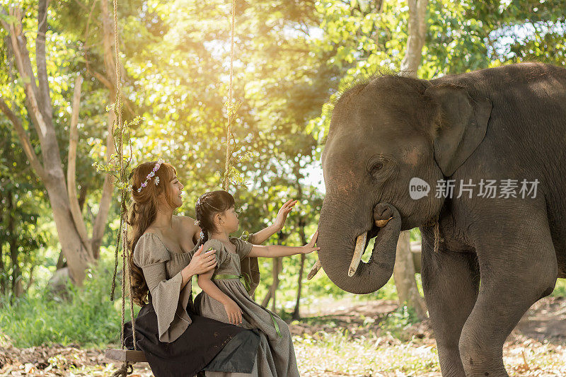 美丽的女人和女孩在大自然中与大象玩耍的肖像艺术