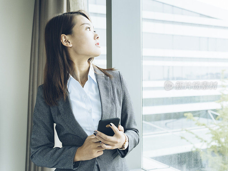 女人站在窗口使用智能手机