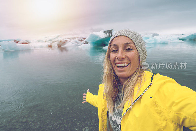 年轻女子与冰川湖自拍，冰山漂浮在水面上