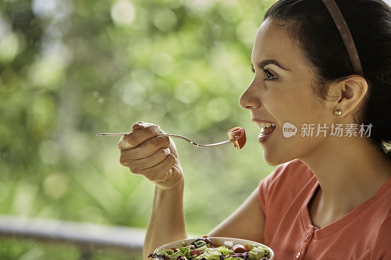 一个西班牙裔可爱的年轻女子午餐吃素食沙拉的特写镜头