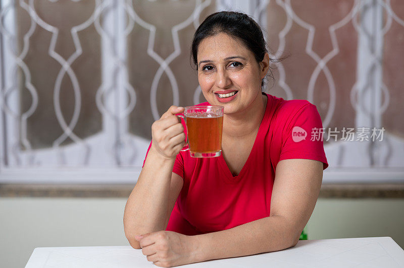 快乐的女人在家里晨练后喝绿茶。