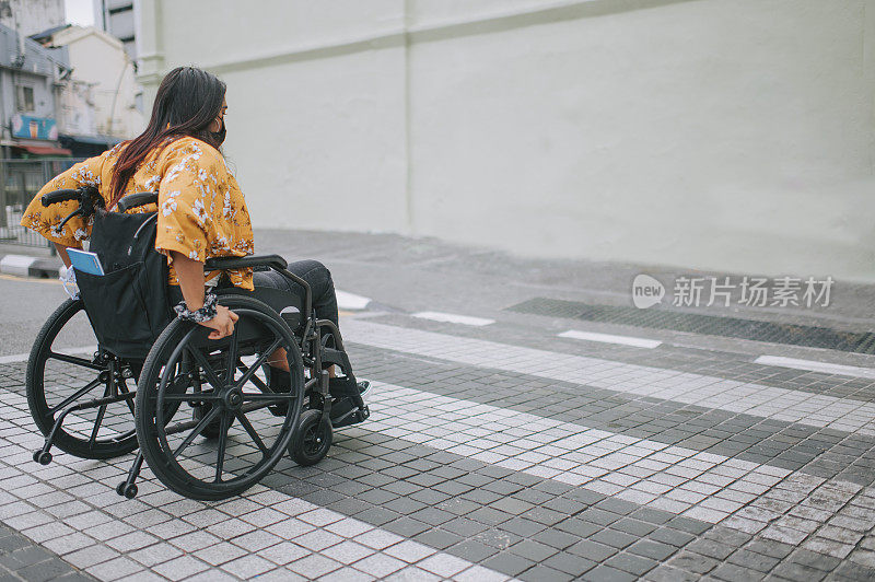 侧视图亚洲印度美丽的妇女残疾人使用轮椅斑马线过马路在城市