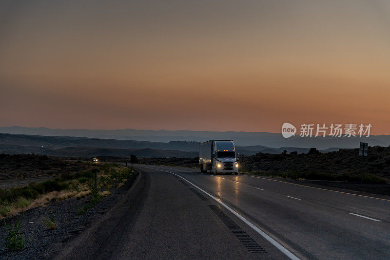 在沙漠高速公路上，一辆卡车向东驶去送东西，一个戏剧性的日落背景