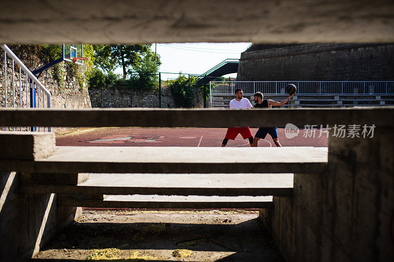 两个年轻人在打街球，从看台后面射门