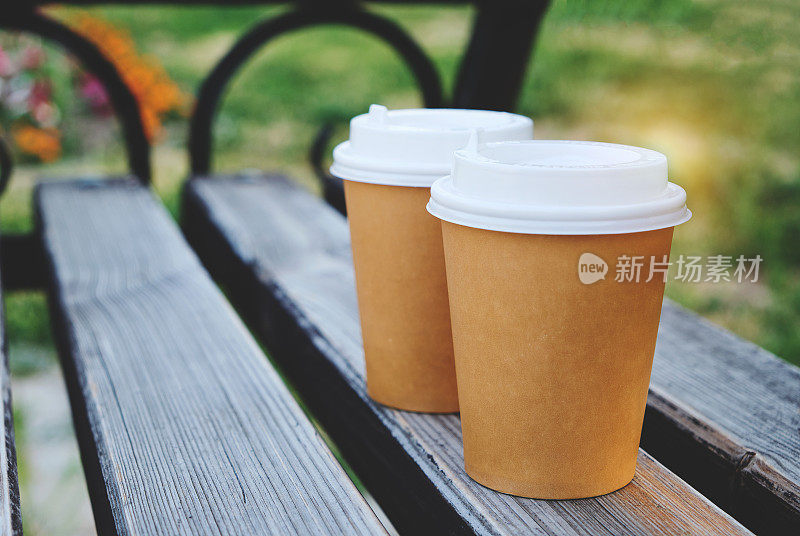 两杯咖啡在公园的木凳上带走