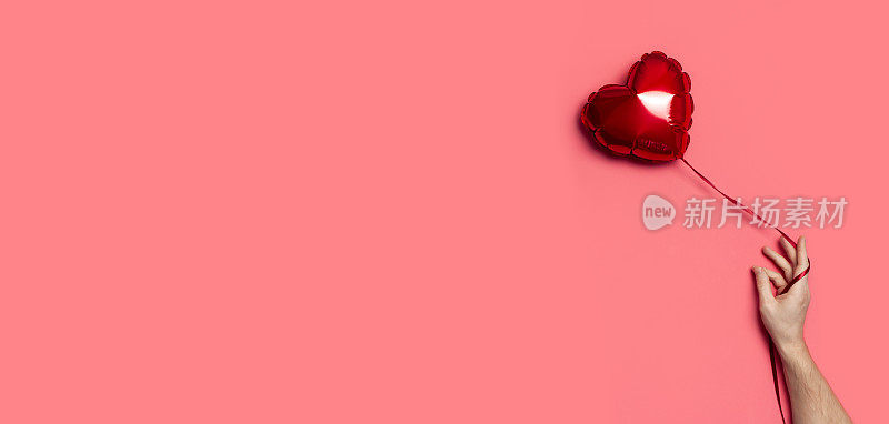 爱的概念。男性手握红色气球在粉红色背景上心形顶视图平面布局复制空间。节日对象，生日，情人节，婚礼。聚会装饰。贺卡