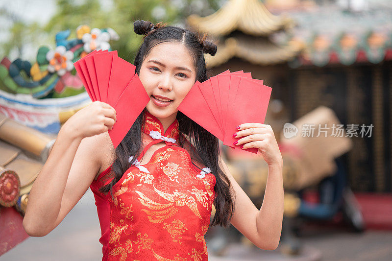 美丽的肖像年轻的亚洲妇女旗袍，微笑着拿着红包