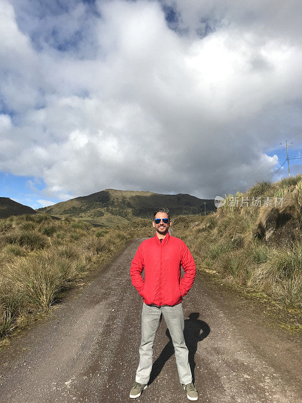 年轻英俊的拉丁男子背包徒步旅行，享受他的假期在塞拉高原上散步和徒步旅行，在中午的时候，在厄瓜多尔基多附近，卡扬贝，科多帕西的皮钦查火山，蓝天。